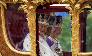 Le roi Charles III salue, aux côtés de la reine Camilla, dans son carrosse lors du cortège royal qui a suivi le couronnement du roi, à Londres, le 6 mai 2023. (LA PRESSE CANADIENNE/Nathan Denette)